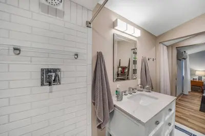 a white bathroom with a sink and a mirror at Luxury Apartment in Historic Carriage House in Kennett Square