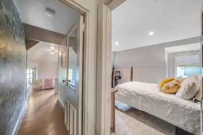 a bedroom with a bed with white sheets and a window at Luxury Loft in Historic Carriage House in Kennett Square