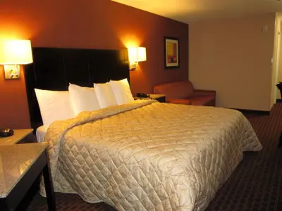 a hotel room with a large bed and a chair at Red Carpet Inn and Suites Monmouth Junction in Monmouth Junction