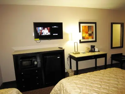 a hotel room with a bed and a television on a wall at Red Carpet Inn and Suites Monmouth Junction in Monmouth Junction
