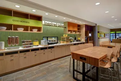 a restaurant with a counter with a table and chairs at Home2 Suites East Hanover, NJ in East Hanover