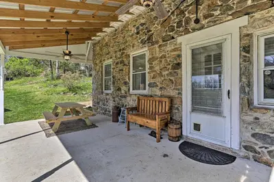 a stone house with a bench on a patio at Patio and Fire Pit Idyllic Cottage in Hellertown! in Bethlehem