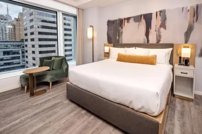 a bedroom with a bed and a chair and a window at Hilton Club The Central at 5th New York in New York