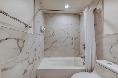 a white bathroom with a tub and a toilet at Sosuite at West Lofts - West Philadelphia in Philadelphia