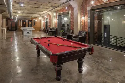 a pool table in an empty room with chairs at Sosuite at West Lofts - West Philadelphia in Philadelphia