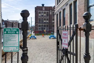 a gate with a dog park and rules signs on it at Sosuite at West Lofts - West Philadelphia in Philadelphia