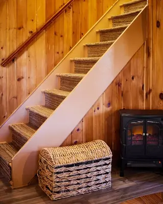 a staircase with a fireplace in a room with wood at Cozy Cottage with Jacuzzi, Sauna, Fire Pit and Reading Nook! in Livingston Manor