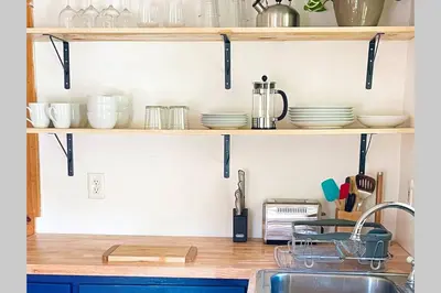a kitchen with wooden shelves with dishes and a sink at Cozy Cottage with Jacuzzi, Sauna, Fire Pit and Reading Nook! in Livingston Manor