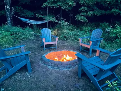 three blue chairs sitting around a fire pit at Cozy Cottage with Jacuzzi, Sauna, Fire Pit and Reading Nook! in Livingston Manor