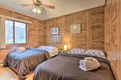 two beds in a room with wooden walls at Resort Perks Picturesque Poconos Getaway! in Bushkill