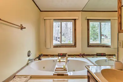 a bathroom with two tubs and a sink and two windows at Resort Perks Picturesque Poconos Getaway! in Bushkill