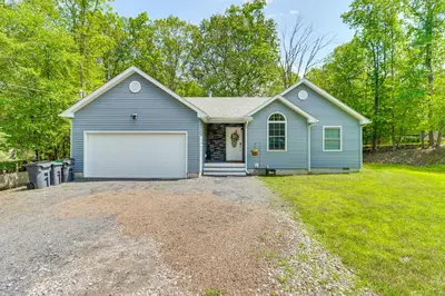 a blue house with a garage in a yard at 7 Mi to Camelback Mtn Chic Penn Estates Home in East Stroudsburg