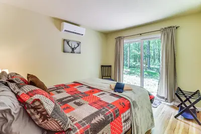 a bedroom with a bed with a blanket and a window at Furnished Deck and Fire Pit Poconos Outdoorsy Gem in Albrightsville