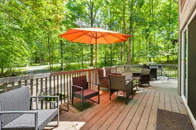 a patio with tables and chairs and an umbrella at Furnished Deck and Fire Pit Poconos Outdoorsy Gem in Albrightsville