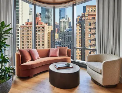 a living room with a couch and a chair and a large window at Pendry Manhattan West in New York