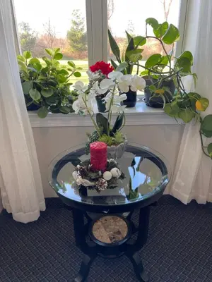a glass table with flowers on it in front of a window at Brinton Suites in West Chester