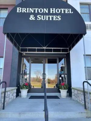 a entrance to a hotel and suites with a blue umbrella at Brinton Suites in West Chester