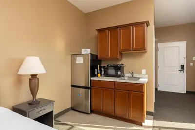 a small kitchen with a refrigerator and a table with a lamp at Brinton Suites in West Chester