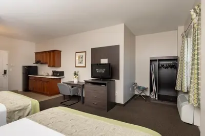 a hotel room with a bed and a desk with a television at Brinton Suites in West Chester