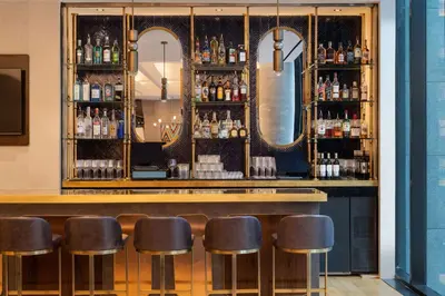 a bar with leather stools and mirrors at Motto by Hilton New York City Chelsea in New York