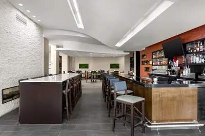 a dining room with a bar and chairs at Embassy Suites by Hilton Newark Airport in Elizabeth