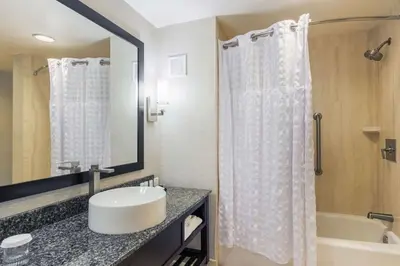 a bathroom with a sink and a tub and a mirror at Embassy Suites by Hilton Newark Airport in Elizabeth