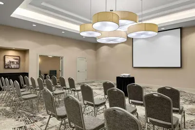 a conference room with a table and chairs and a screen at Embassy Suites by Hilton Newark Airport in Elizabeth
