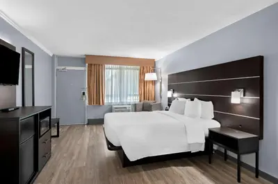 a hotel room with a white bed and a television at Brandywine Valley Inn SureStay Plus by Best Western in Wilmington