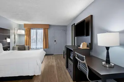 a hotel room with a bed and a desk with a lamp at Brandywine Valley Inn SureStay Plus by Best Western in Wilmington
