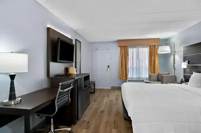 a hotel room with a bed and a desk and a tv at Brandywine Valley Inn SureStay Plus by Best Western in Wilmington