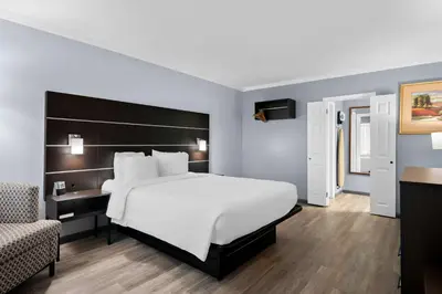 a bedroom with a large white bed and a chair at Brandywine Valley Inn SureStay Plus by Best Western in Wilmington