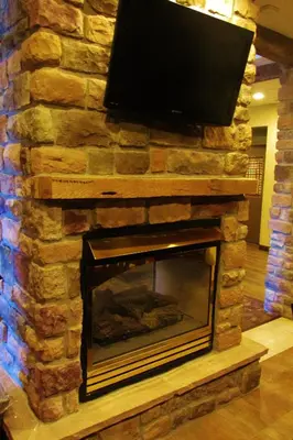 a stone fireplace with a television on top of it at Crystal Springs Inn and Suites in Towanda