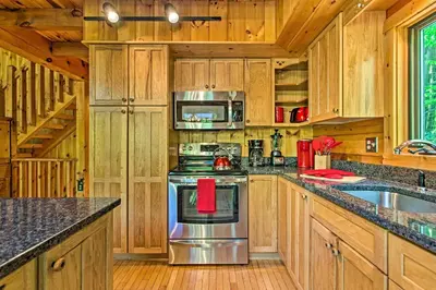 a kitchen with wooden cabinets and a stainless steel stove at Fire Pit and Hot Tub Poconos Family Cabin! in Long Pond