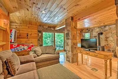 a living room with a couch and a flat screen tv at Fire Pit and Hot Tub Poconos Family Cabin! in Long Pond