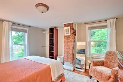 a bedroom with a bed and a chair and windows at Charming Abode with Patio - Walk to Town and River! in Stockton