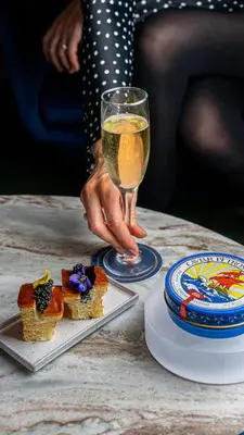 a person holding a glass of wine next to a table with food at The Wallace Hotel in New York