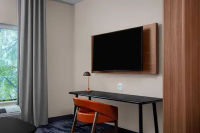 a hotel room with a desk and a television on the wall at Fairfield by Marriott Inn & Suites Lewisburg in Lewisburg