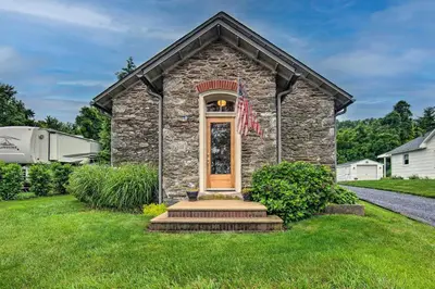 a stone house with a flag on the front of it at Private Hot Tub at Cozy Wrightsville Cottage! in Wrightsville