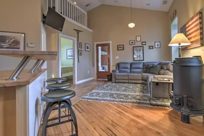 a living room with a couch and a bar with stools at Private Hot Tub at Cozy Wrightsville Cottage! in Wrightsville