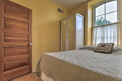 a bedroom with a bed with a wooden door and a window at Private Hot Tub at Cozy Wrightsville Cottage! in Wrightsville