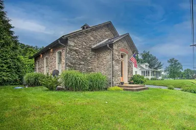 a stone house with a flag in a yard at Private Hot Tub at Cozy Wrightsville Cottage! in Wrightsville