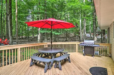 a picnic table with a red umbrella on a deck at Sunroom, Fire Pit and Sauna Lake Locust Village Gem in Pocono Lake