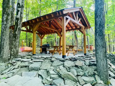 a wooden pavilion with a picnic table in the woods at Lakeview Cabin in The Hideout in Lake Ariel