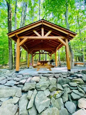a wooden pavilion with a picnic table in a forest at Lakeview Cabin in The Hideout in Lake Ariel
