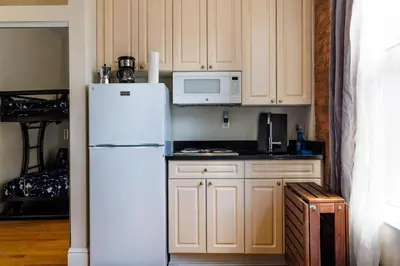 a kitchen with white cabinets and a white refrigerator at Studios in New York in New York