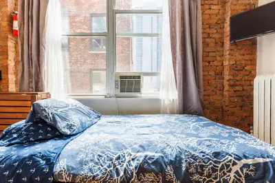 a bed with a blue comforter in front of a window at Studios in New York in New York