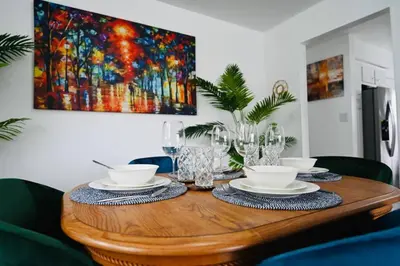 a dining room table with a painting on the wall at Bright & cozy * 2nd Floor Apartment*. Close to NYC in Bloomfield