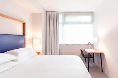 a bedroom with a bed and a desk and a window at The Standard - East Village in New York