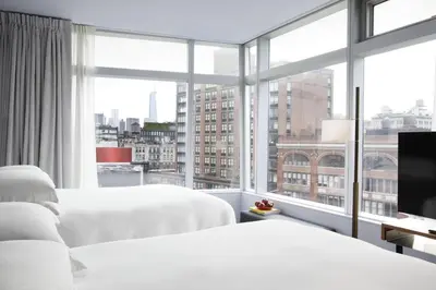 two beds in a hotel room with a large window at The Standard - East Village in New York