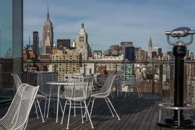 a balcony with chairs and tables and a view of a city at The Standard - East Village in New York